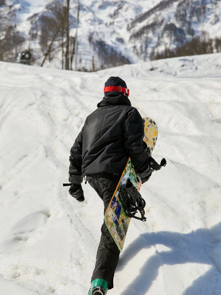 A splitboarder ascends a skin track through an alpine glade.